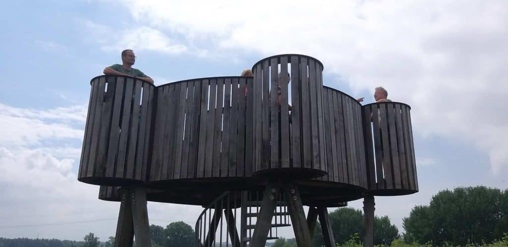 Houten uitkijktoren op 't Gelders Eiland met drie mensen die genieten van het uitzicht.