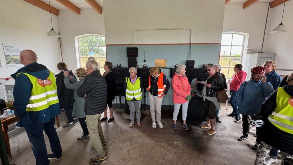 Hoge bezoekersgroep bij binnenactiviteit op 't Gelders Eiland, met mensen in veiligheidsvesten en ee.