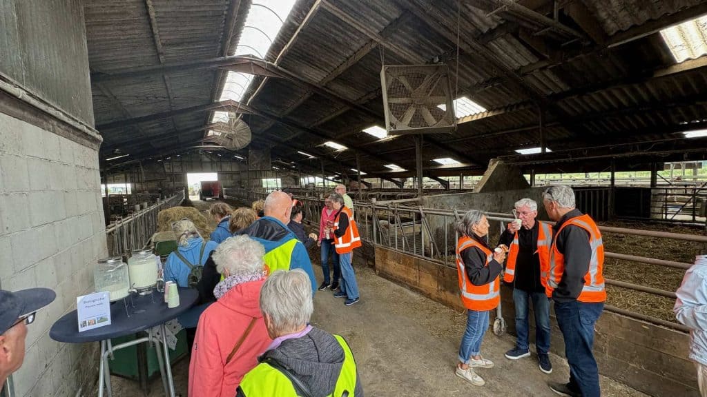 De afbeelding toont een groep mensen in een binnenruimte van een boerderij, met enkele personen die.