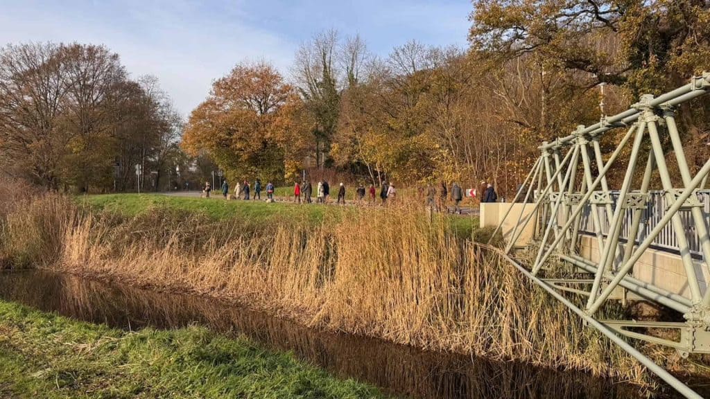Zicht op 't Gelders Eiland met wandelende bezoekers en een brug in de natuur in de herfst.