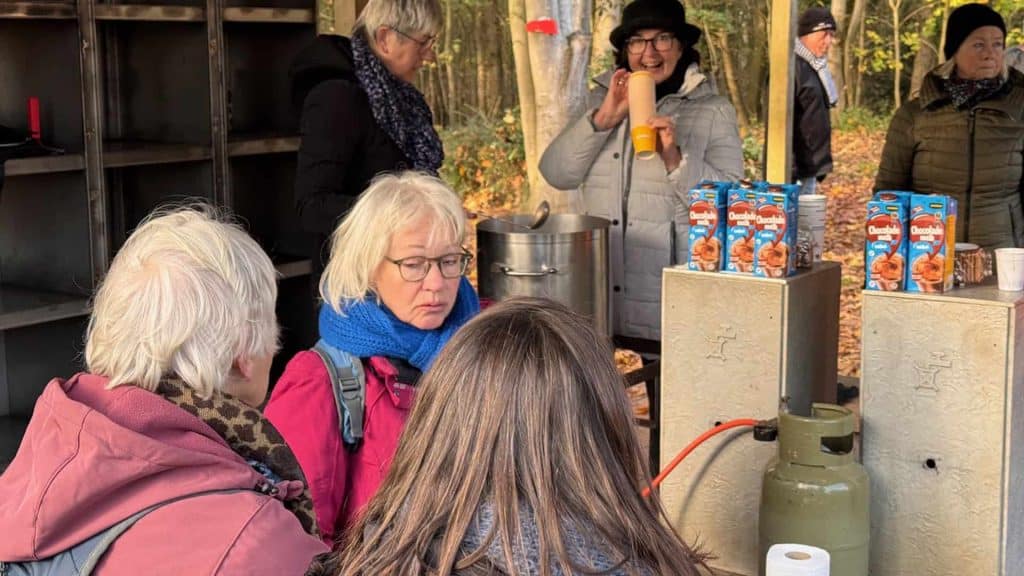 Gezellige groep mensen geniet van warme dranken bij een buitenkraam op 't Gelders Eiland in de herfs.