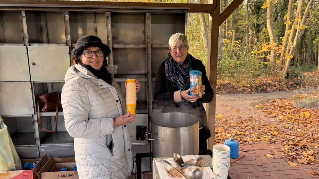 Gezellige herfstmarkt op 't Gelders Eiland met twee vrouwen die warme dranken serveren.