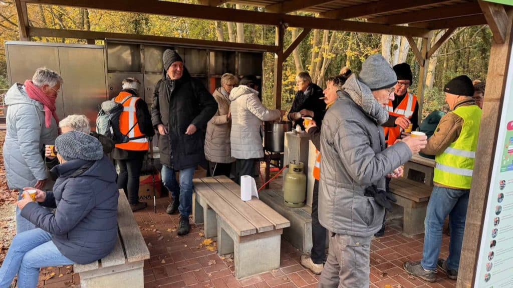Gezellige markt op 't Gelders Eiland met bezoekers en verkopers in een houten kiosk.