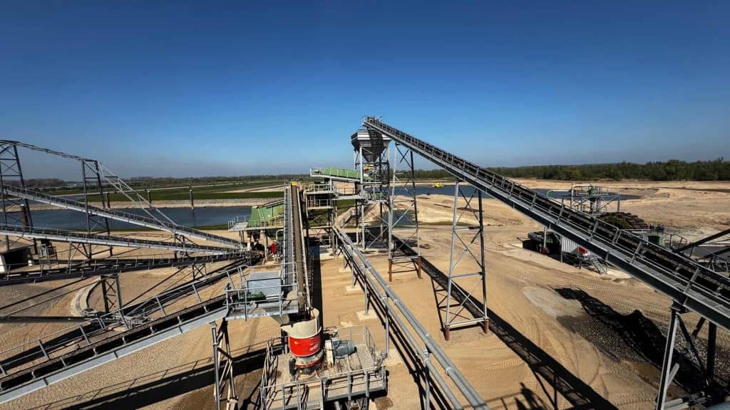 Zandwinning op 't Gelders Eiland met industriële graafmachines en conveyorbanden.