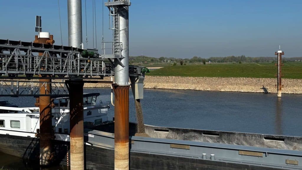 Scheepvaart op de rivier met industriële infrastructuur op 't Gelders Eiland.