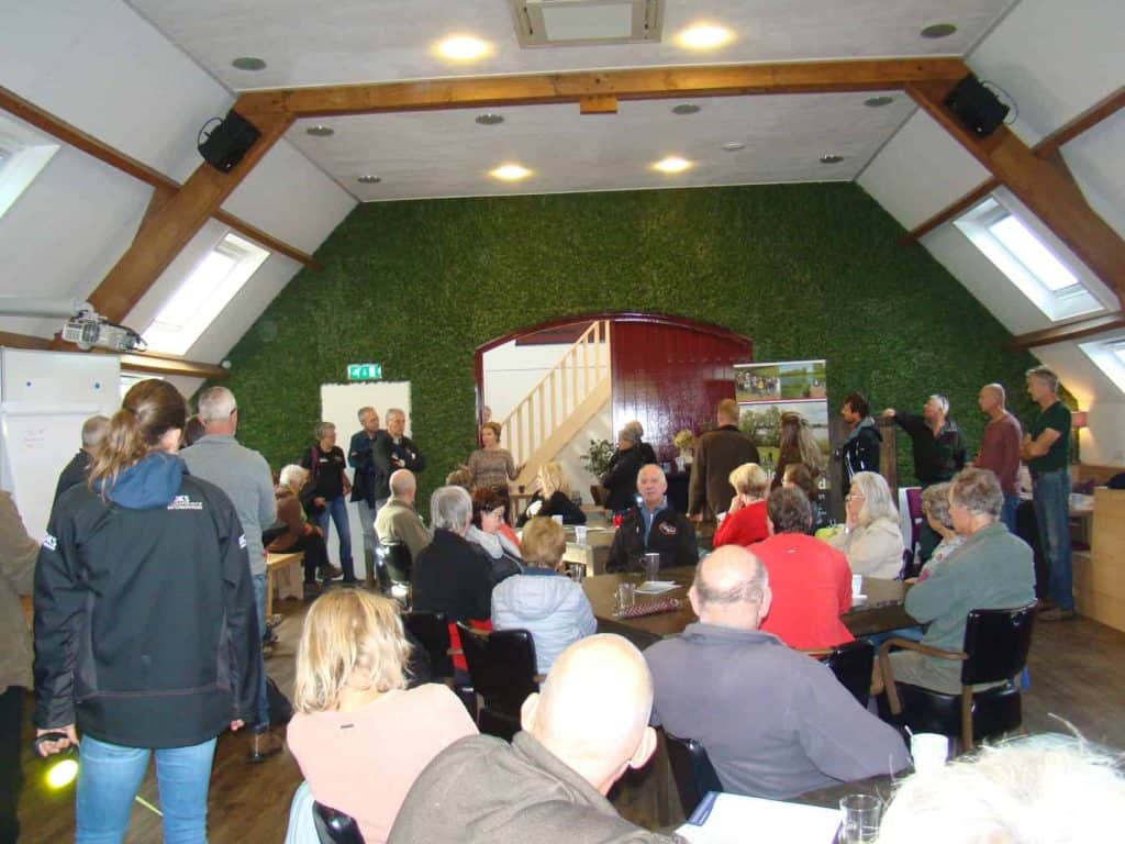 Gezellige bijeenkomst in een zaal op 't Gelders Eiland met mensen die praten en genieten.