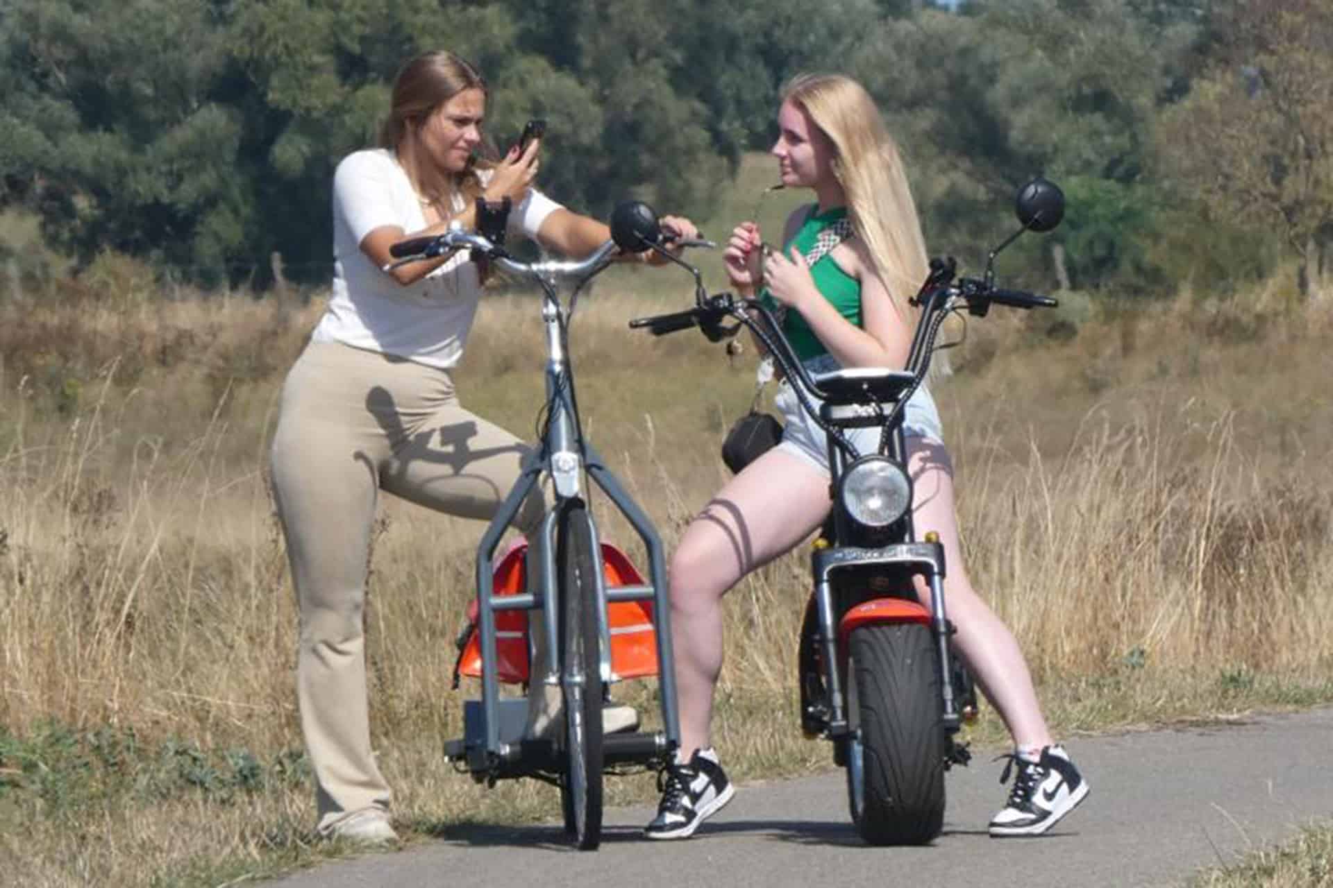 Twee jonge vrouwen met elektrische fiets en scooter op 't Gelders Eiland, genieten van de natuur.