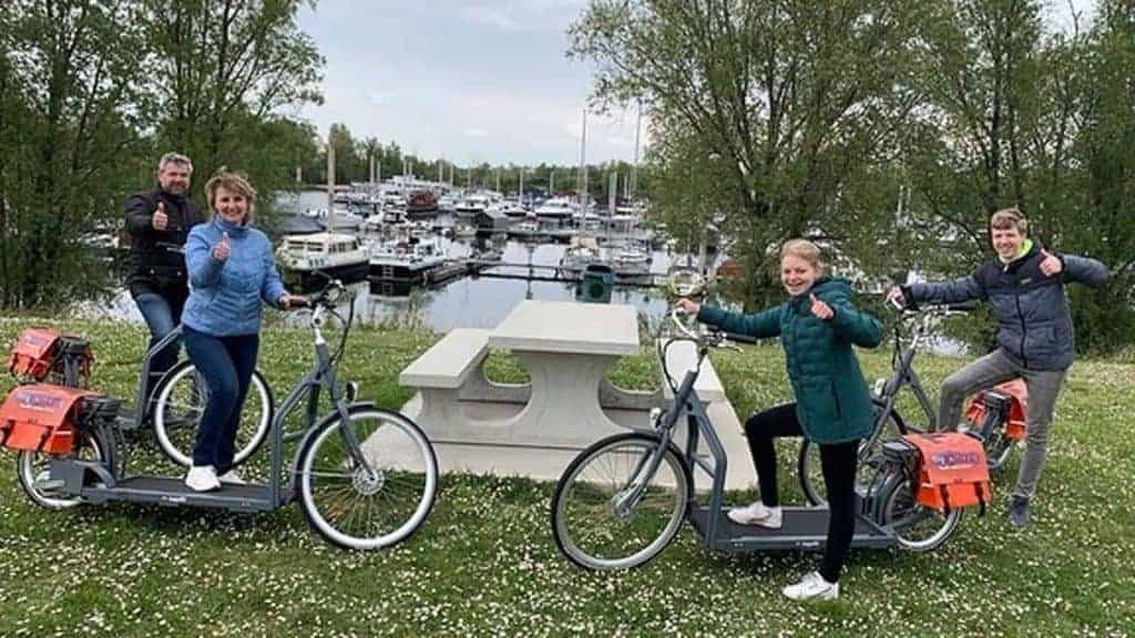 Gezinnen genieten van fietsen en varen op 't Gelders Eiland, met uitzicht op de haven en groene omge.