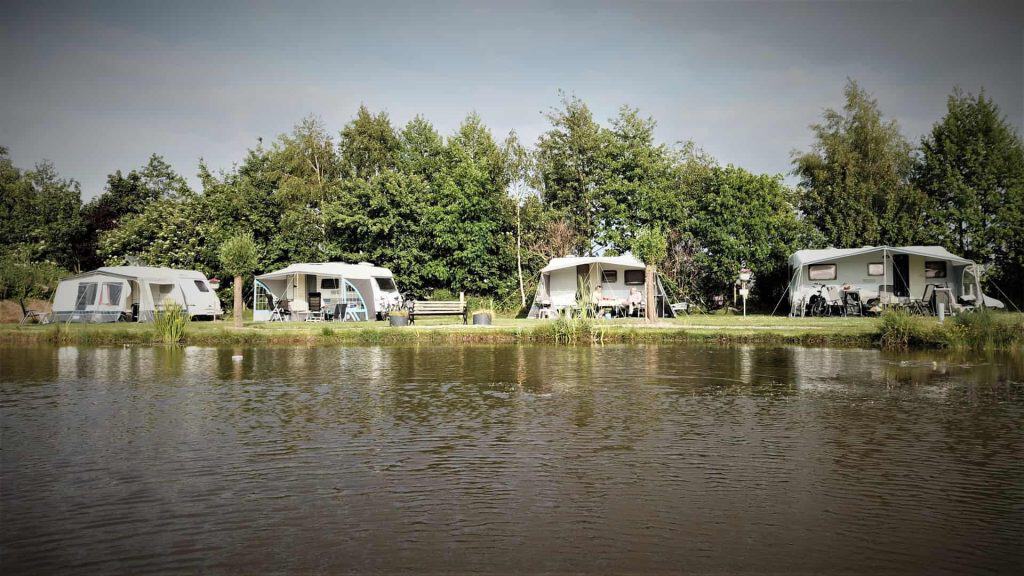 Veiligstacaravans langs de rivier op 't Gelders Eiland, omgeven door groen en water.
