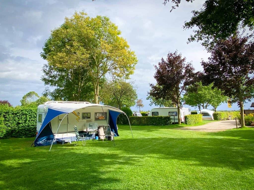 Kampeerplek met tent en caravans op groen grasland op 't Gelders Eiland.