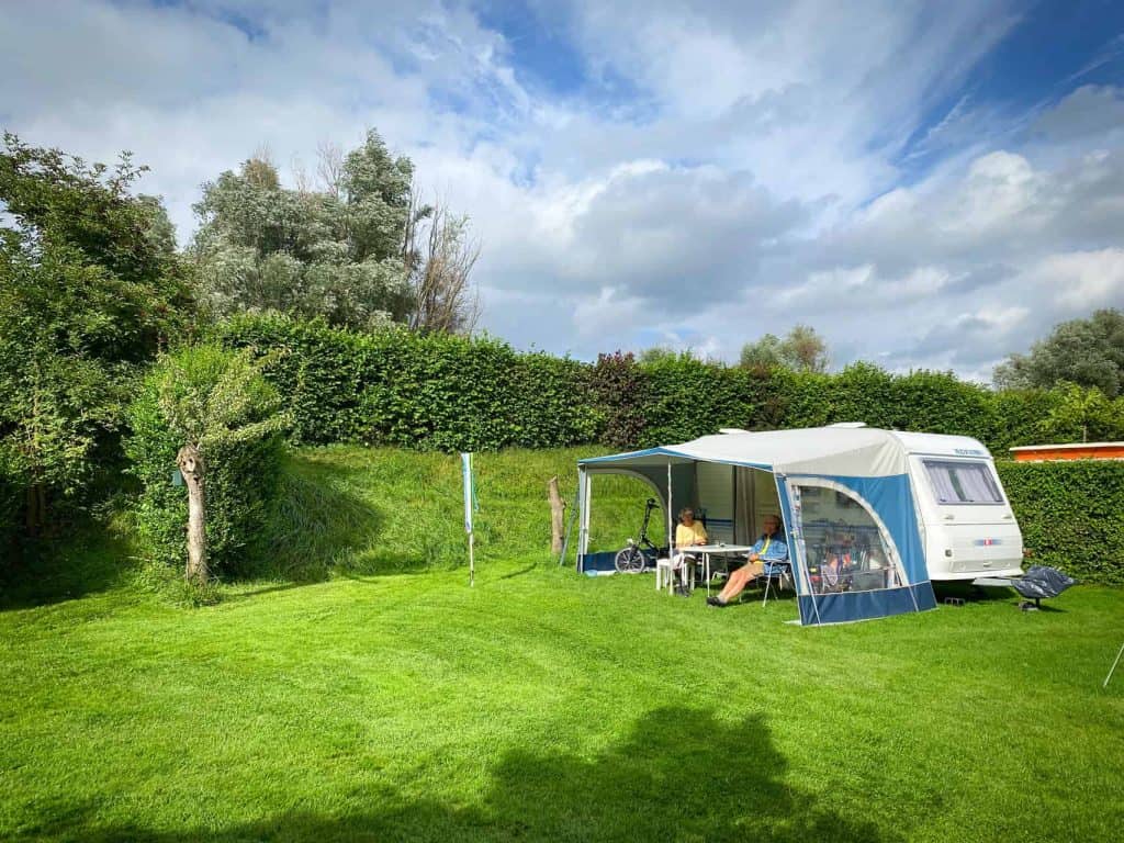 Gezellig kamperen met caravan en tent op groen grasveld op 't Gelders Eiland.