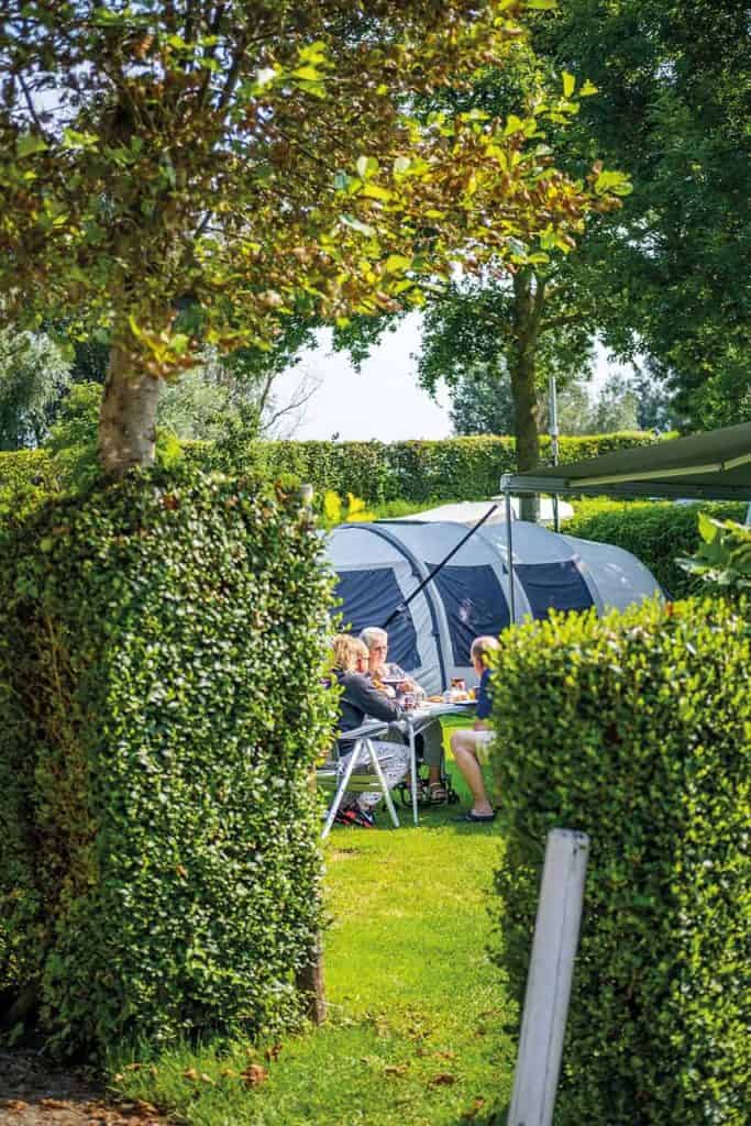 Kampeerplek met tent en zitje in groene tuin op 't Gelders Eiland.