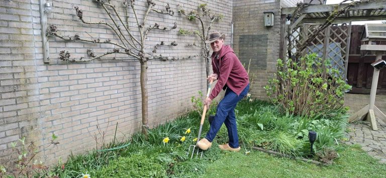Een man die in een tuin op 't Gelders Eiland aan het tuinieren is.