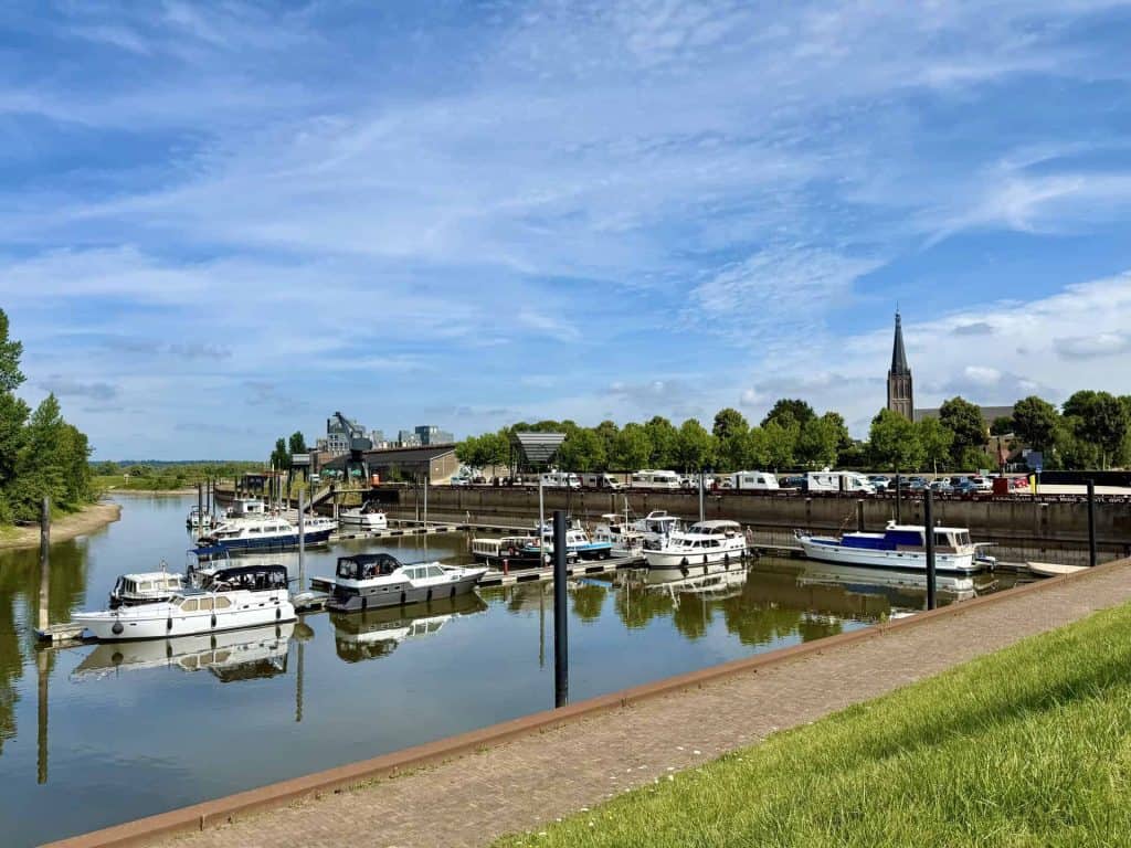 Haven met boten en kerktoren op 't Gelders Eiland, met blauwe lucht en groene omgeving.
