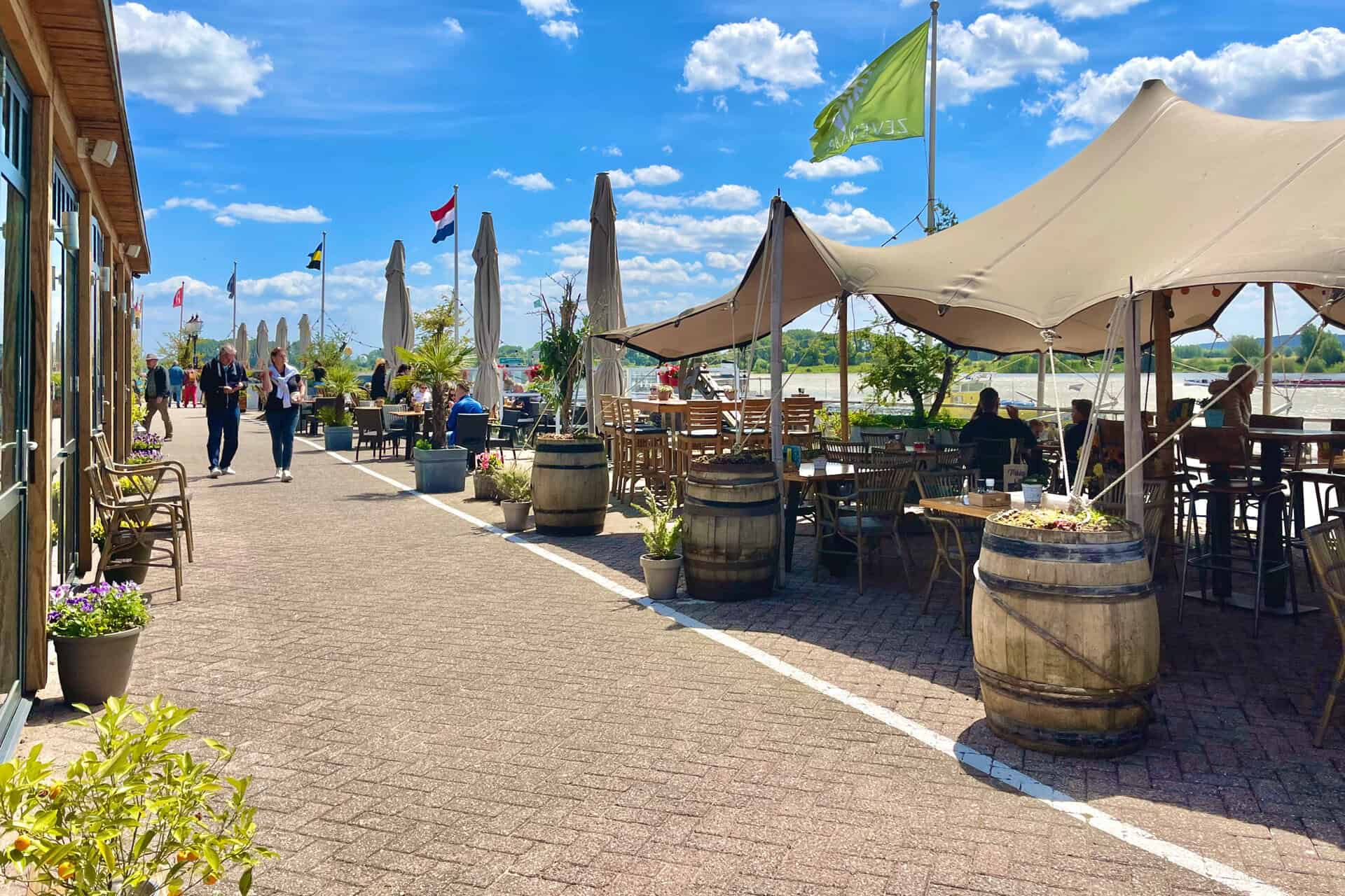 Gezellig terras met tenten en vlaggen op 't Gelders Eiland, ideaal voor ontspanning en genieten van.