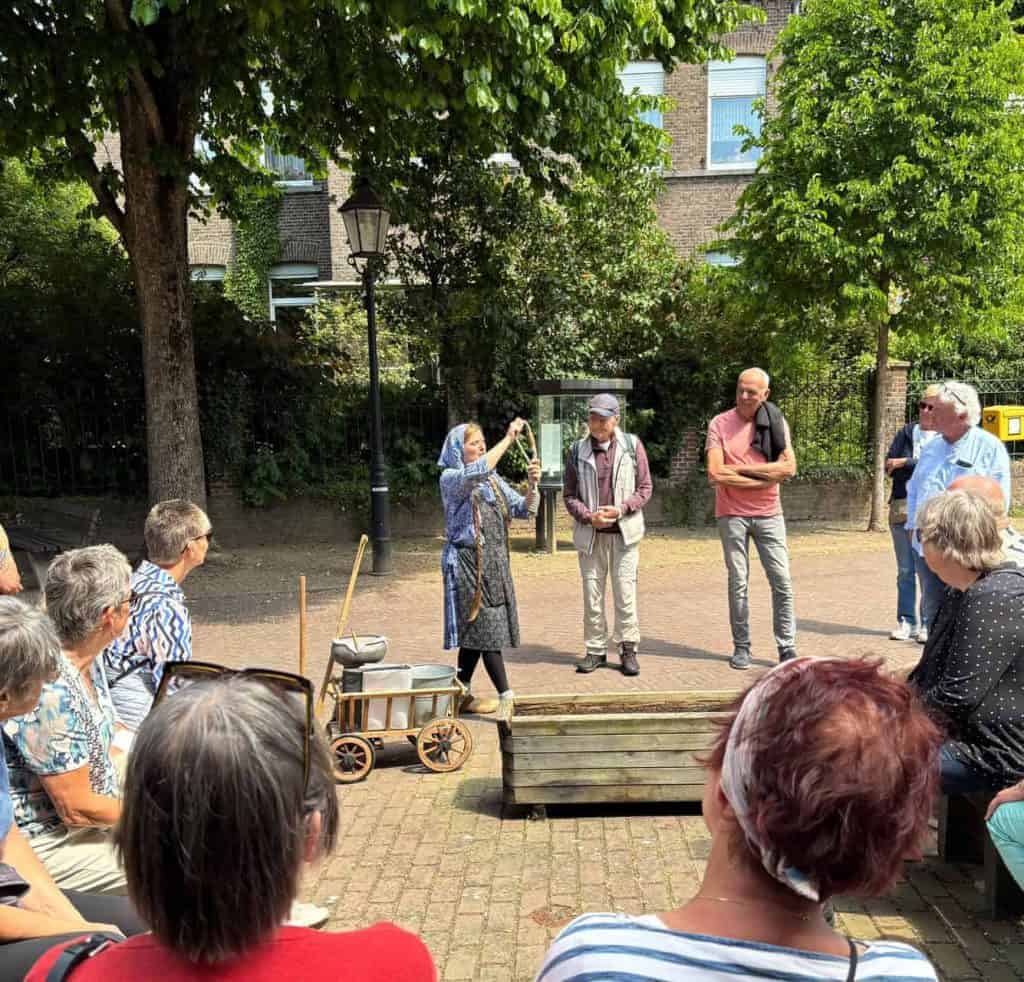 Een groep ouderen luistert naar een gids tijdens een rondleiding op 't Gelders Eiland, omgeven door.