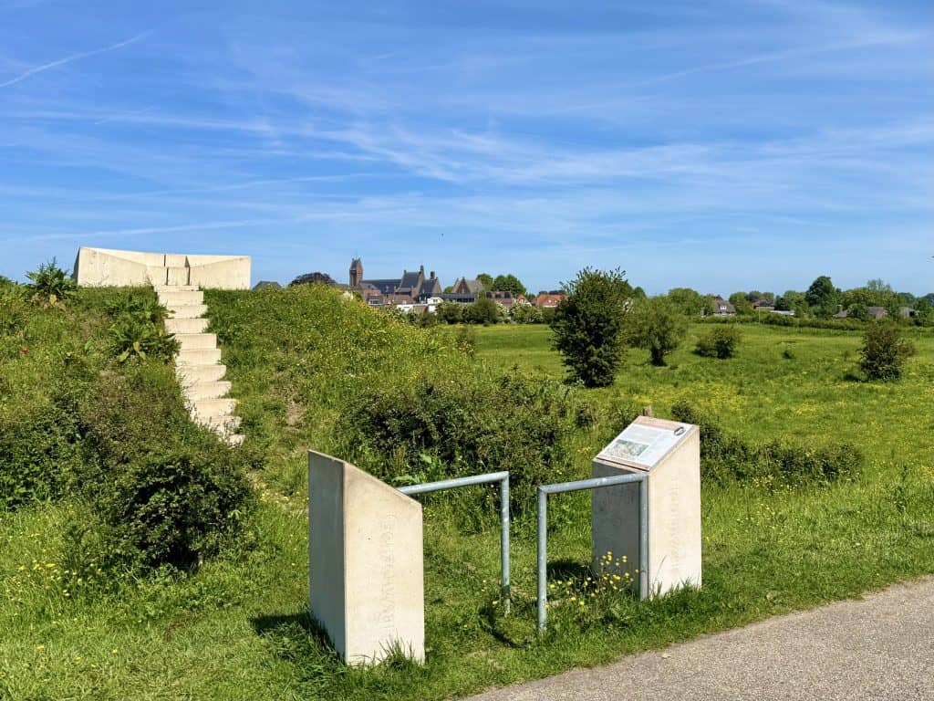 Uitzicht op 't Gelders Eiland met informatiebord en trap in groene omgeving.