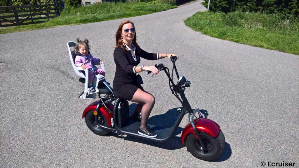 Vrouw rijdt op elektrische scooter met kind achterop op 't Gelders Eiland.