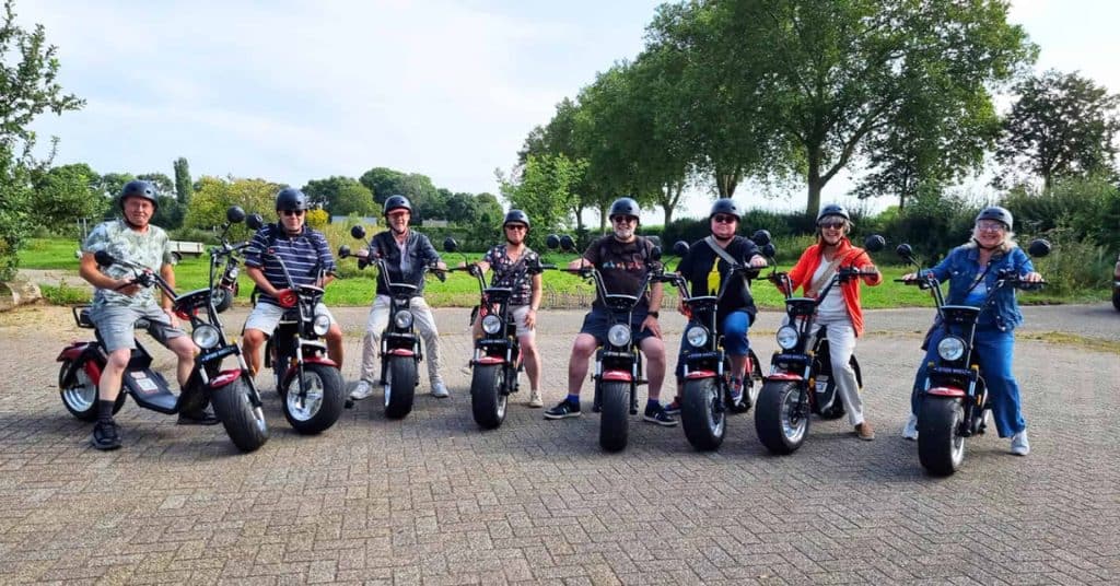 Groep mensen op elektrische scooters op 't Gelders Eiland in de buitenlucht.