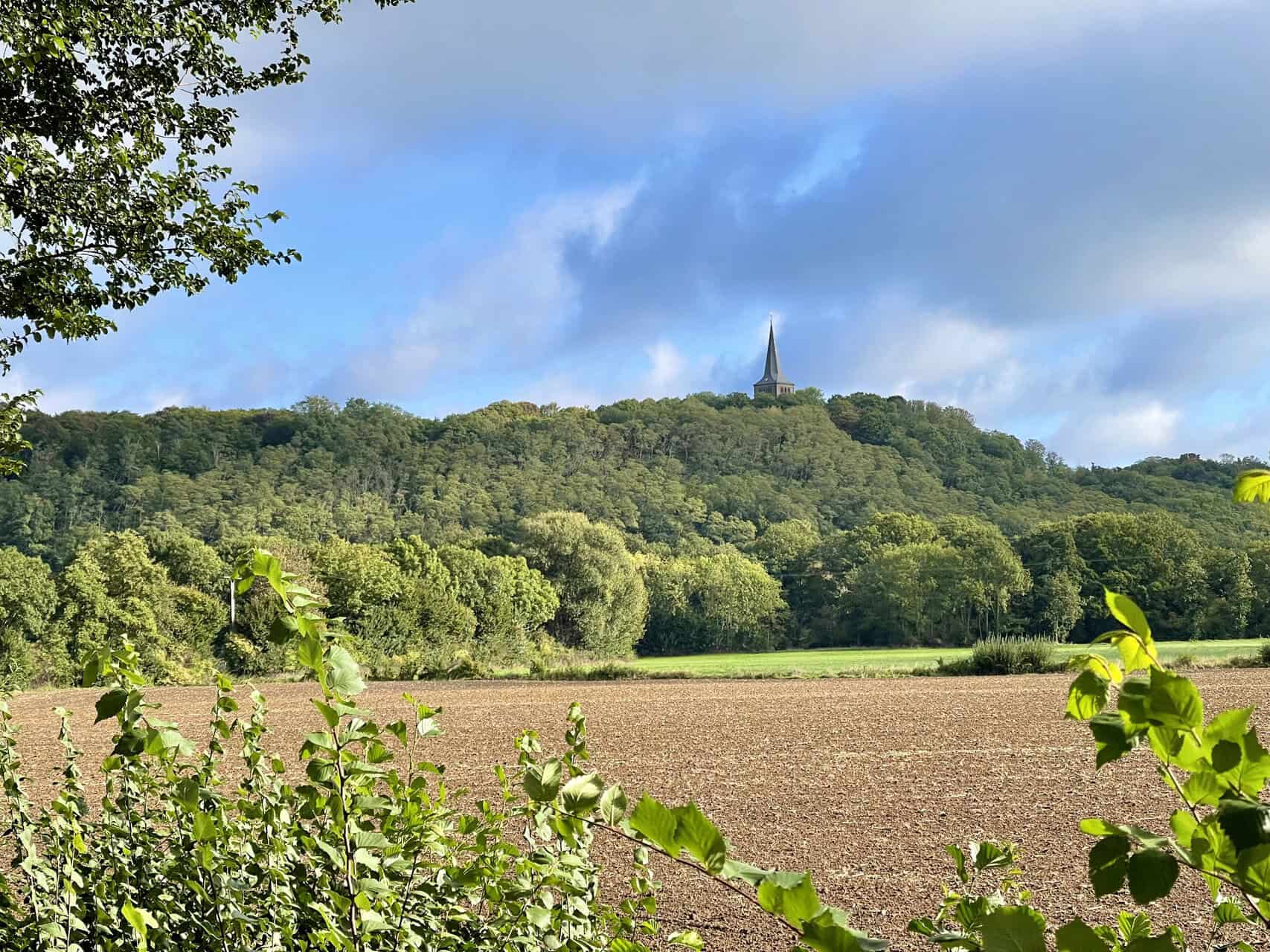 Kerk op 't Gelders Eiland met groene velden en blauwe lucht, omgeven door natuur en landbouwgebieden.