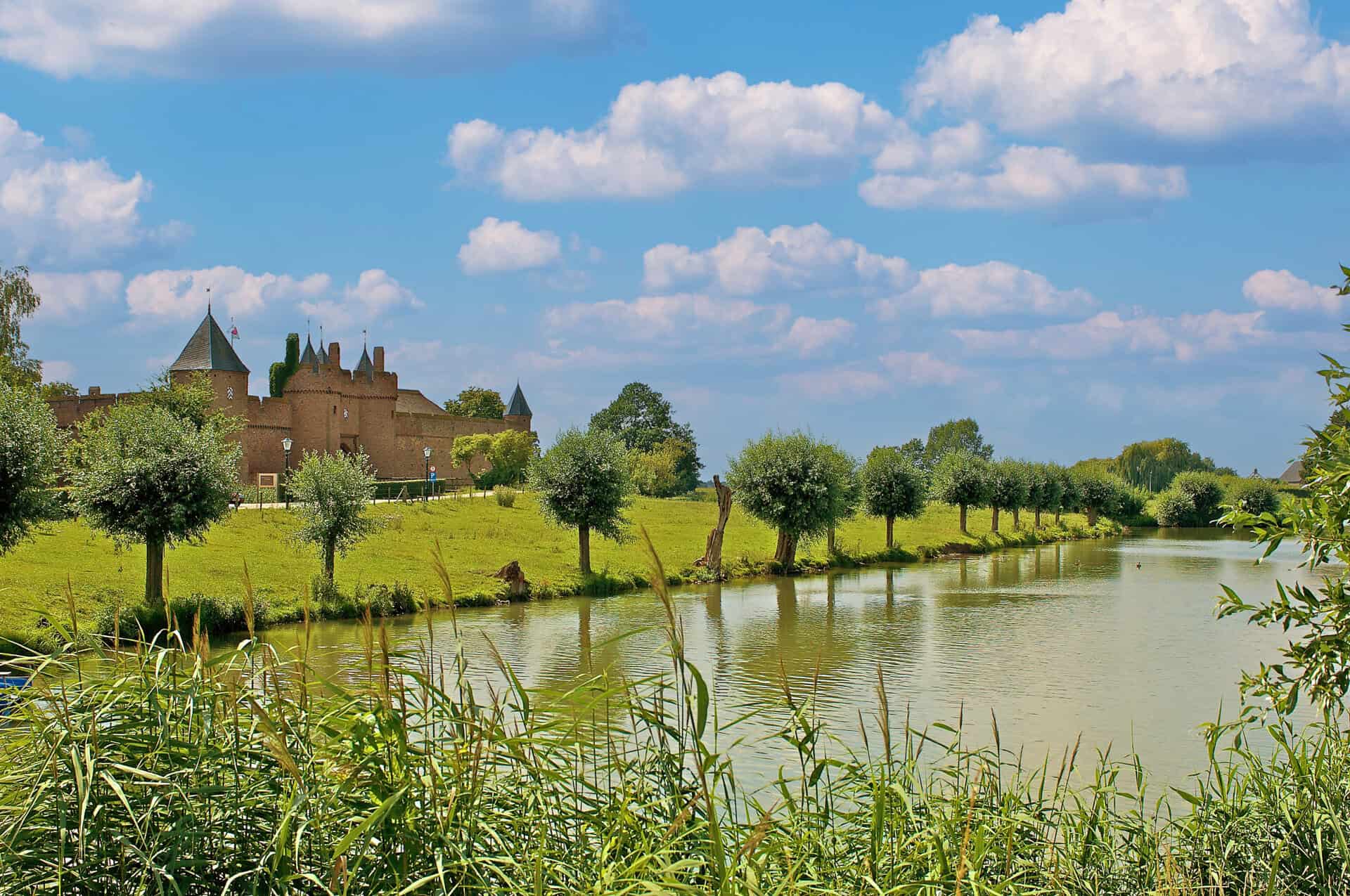 Kasteel op 't Gelders Eiland met rivier en groene omgeving onder een blauwe hemel.
