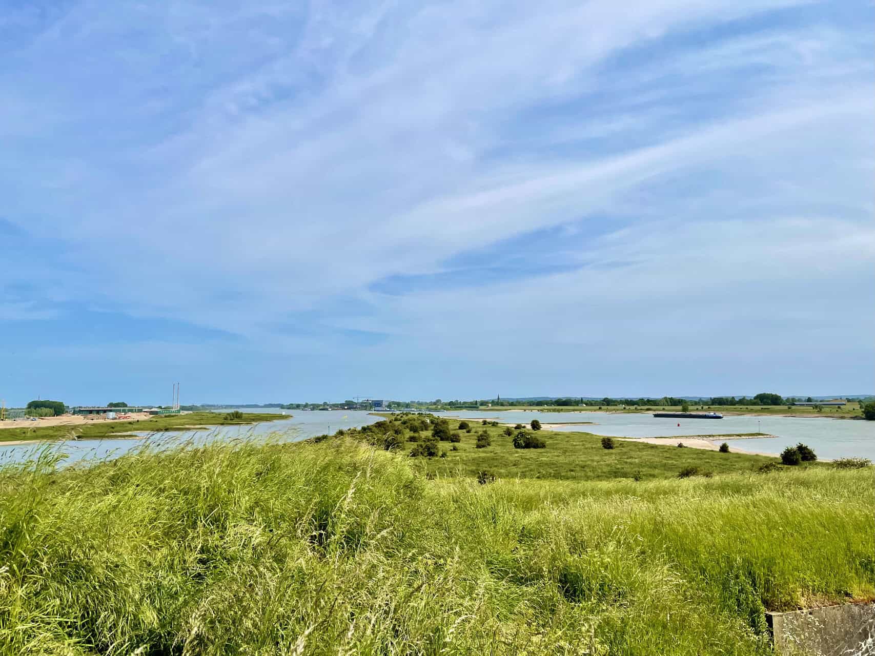 Gelders Eiland landschap met water, gras en blauwe lucht, typisch natuurgebied in Nederland.