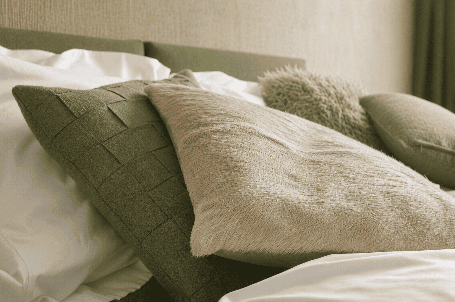 Gezellige slaapkamer met groene en beige kussens op een bed.