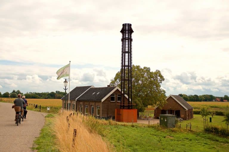 Fietsers op pad langs het historische landschap van 't Gelders Eiland met molen en weilanden.