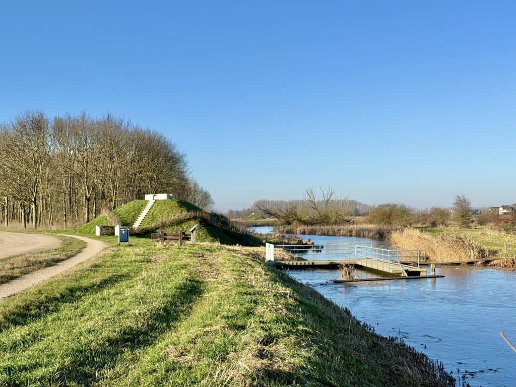 Uitzicht op de historische vesting en de rivier op 't Gelders Eiland, met groene grasvelden en wande.