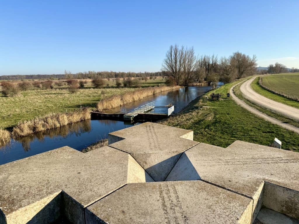 Gelders Eiland landschap met water, paden en rustieke omgeving onder een heldere blauwe lucht.