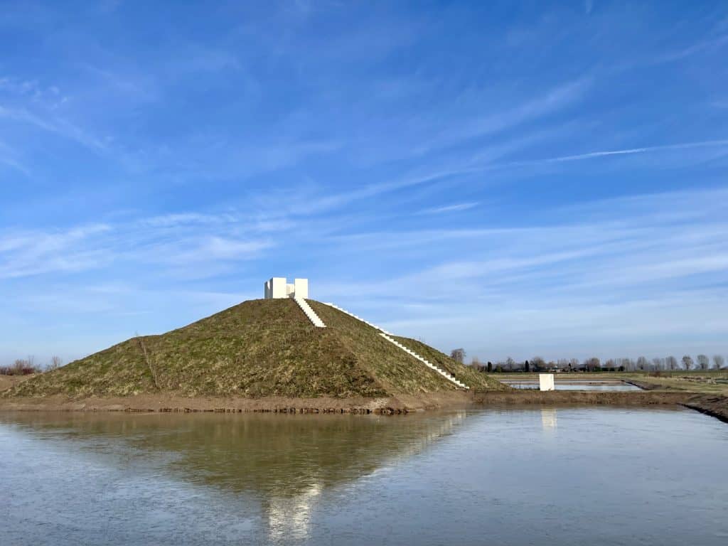 Uitzicht op 't Gelders Eiland met water en een witte toren op de heuvel.