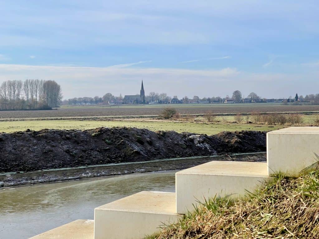 Uitzicht op het platteland en de rivier op 't Gelders Eiland met een kerktoren op de achtergrond.