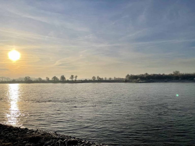 Zonsondergang over 't Gelders Eiland, rustige rivier en open hemel.