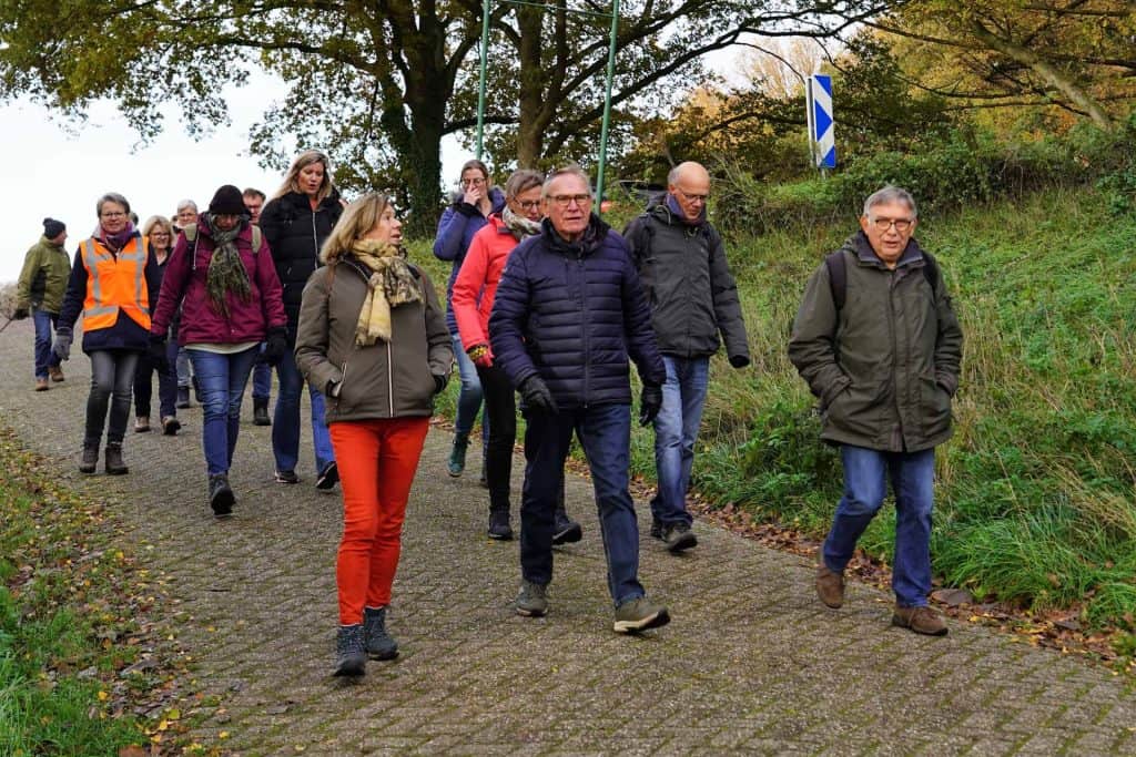 Gezelschap wandelaars op 't Gelders Eiland in de natuur, herfstkleuren en ontspannen sfeer.