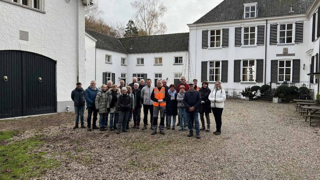Heren en dames in groep voor historisch gebouw op 't Gelders Eiland.