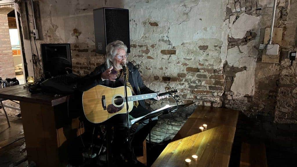 Zanger speelt akoestische gitaar tijdens live optreden in een industrieel interieur.