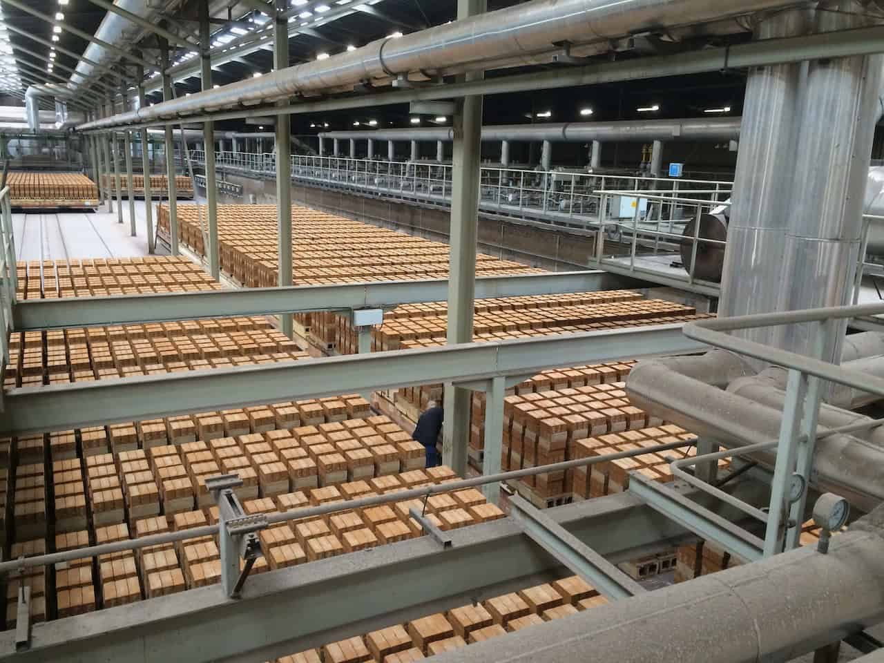 Binnenzicht van houtproductieproces bij 't Gelders Eiland, met stapels houtplanken en industriële ap.