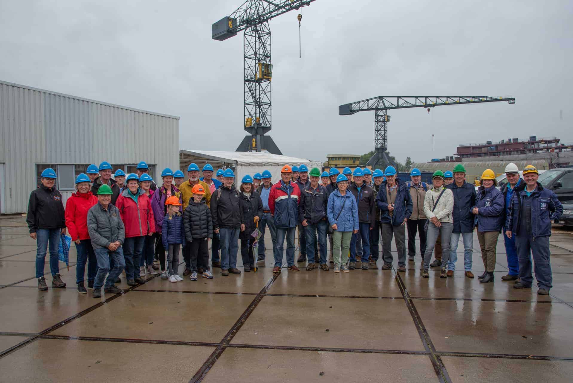 Groep mensen met helmen op bouwplaats op 't Gelders Eiland, onder grote bouwkranen.