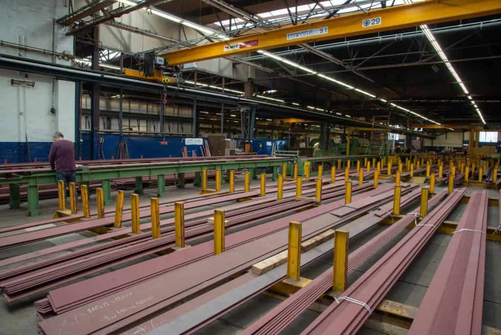 Lage binnenkant van een staalfabriek met metalen balken en hijskraan.