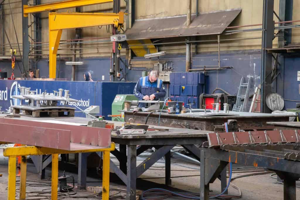 Metaalbewerking in een industriële werkplaats op 't Gelders Eiland, met een technicus die aan een me.