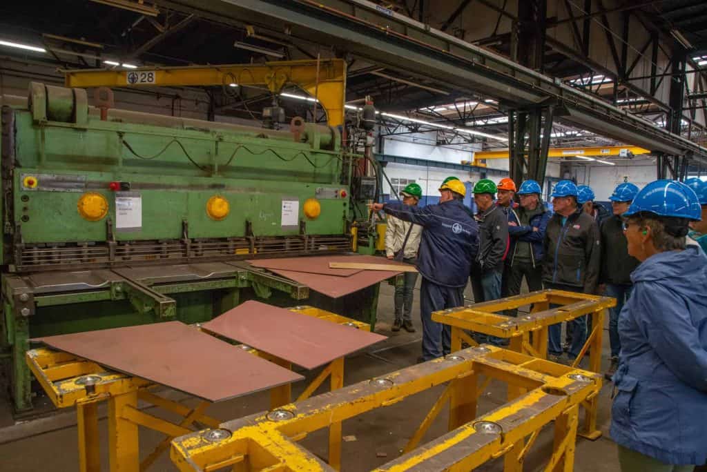 Industriële productie met werknemers in veiligheidskleding en machines.