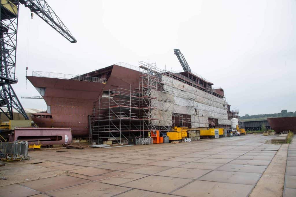 Bouw van een schip op 't Gelders Eiland, met steigers en bouwmaterialen zichtbaar.