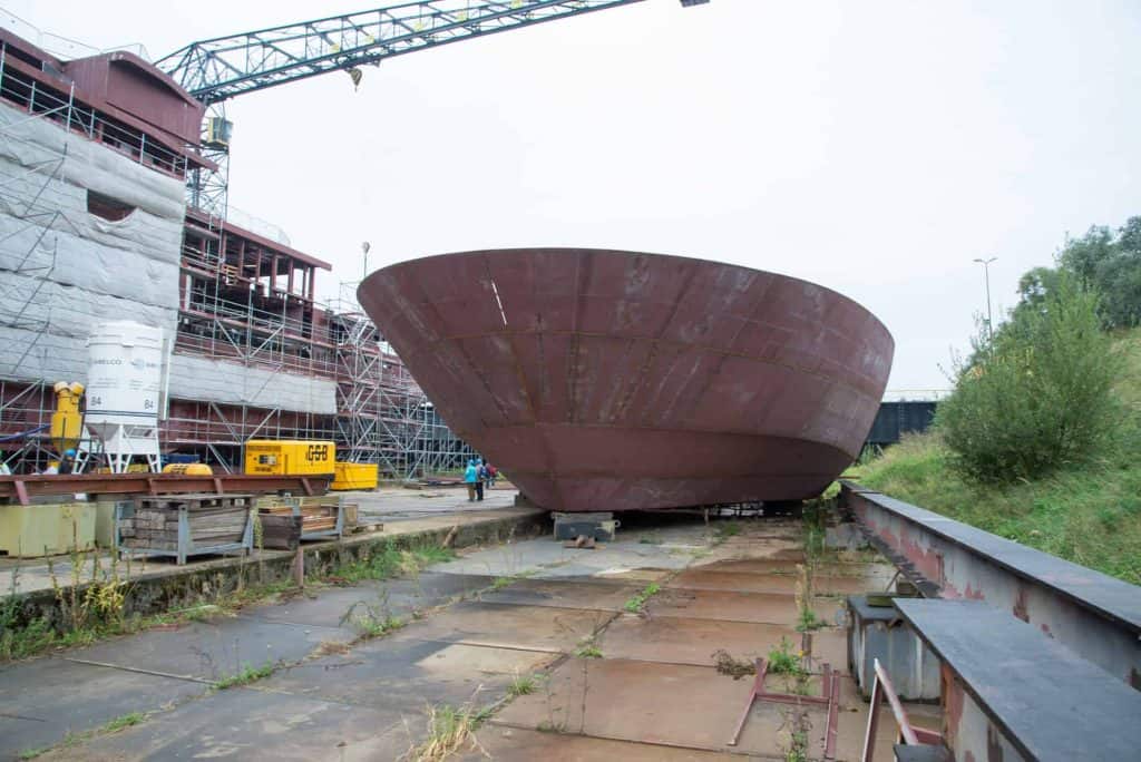 Oud schip in aanbouw op 't Gelders Eiland, scheepswerf met bouw- en constructiewerkzaamheden.
