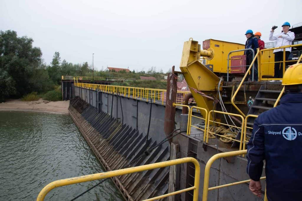 Drijvende dam op 't Gelders Eiland met technici en inspecteurs in veiligheidskleding.