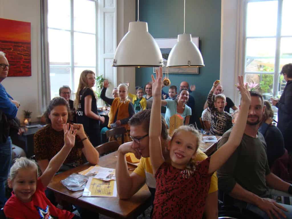 Gezellige groep kinderen en volwassenen in een restaurant op 't Gelders Eiland, genietend van een le.