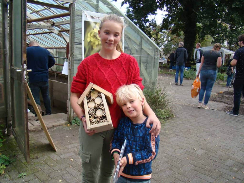Een jonge vrouw en een jongen met een insectenhotel op 't Gelders Eiland. Groene omgeving en bezoeke.