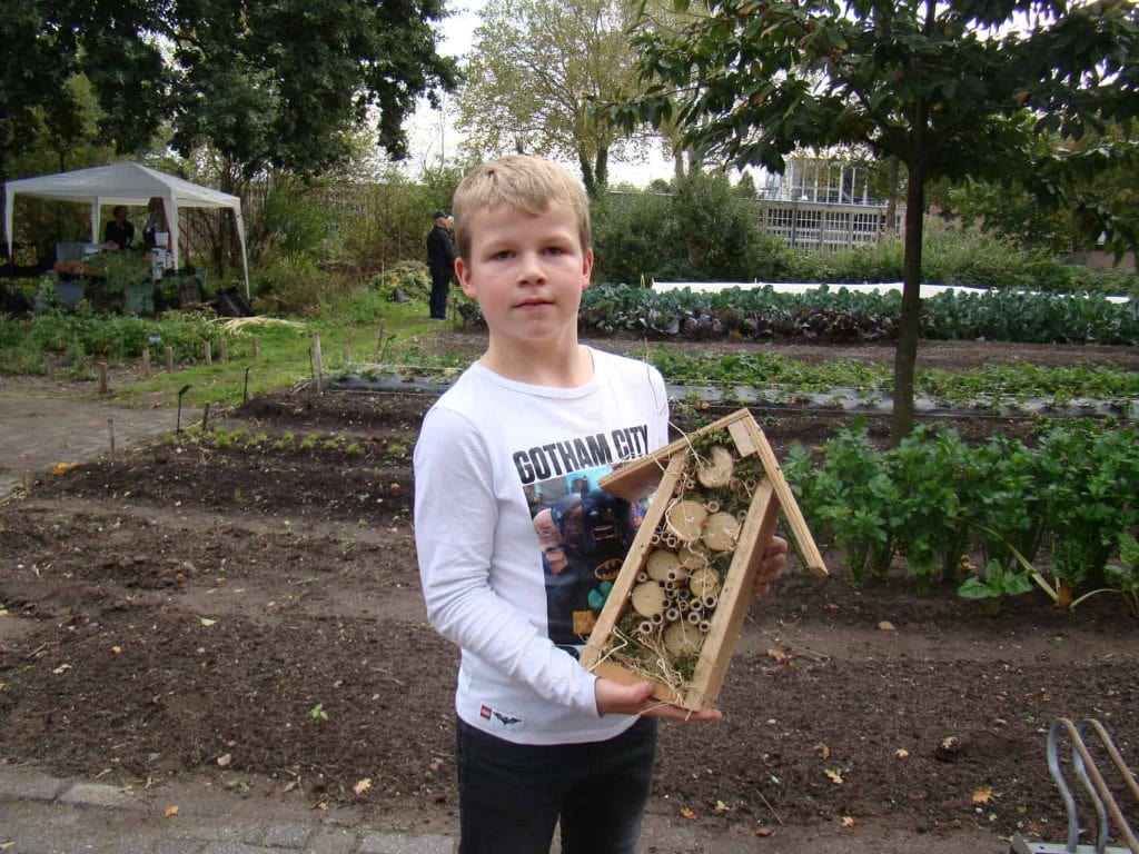 Een jonge jongen houdt een insectenhotel in een tuin op 't Gelders Eiland.