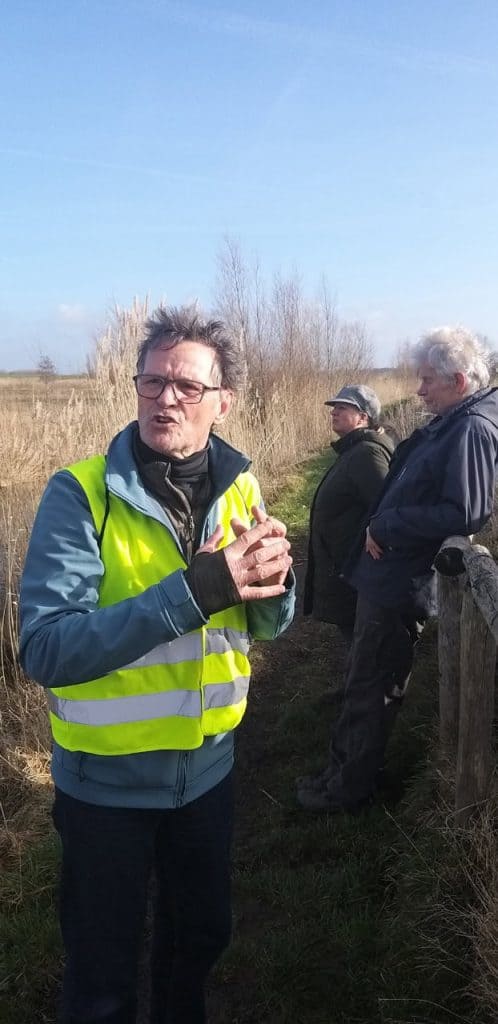 Heren in groene veiligheidsvesten wandelen en praten buiten op het platteland.