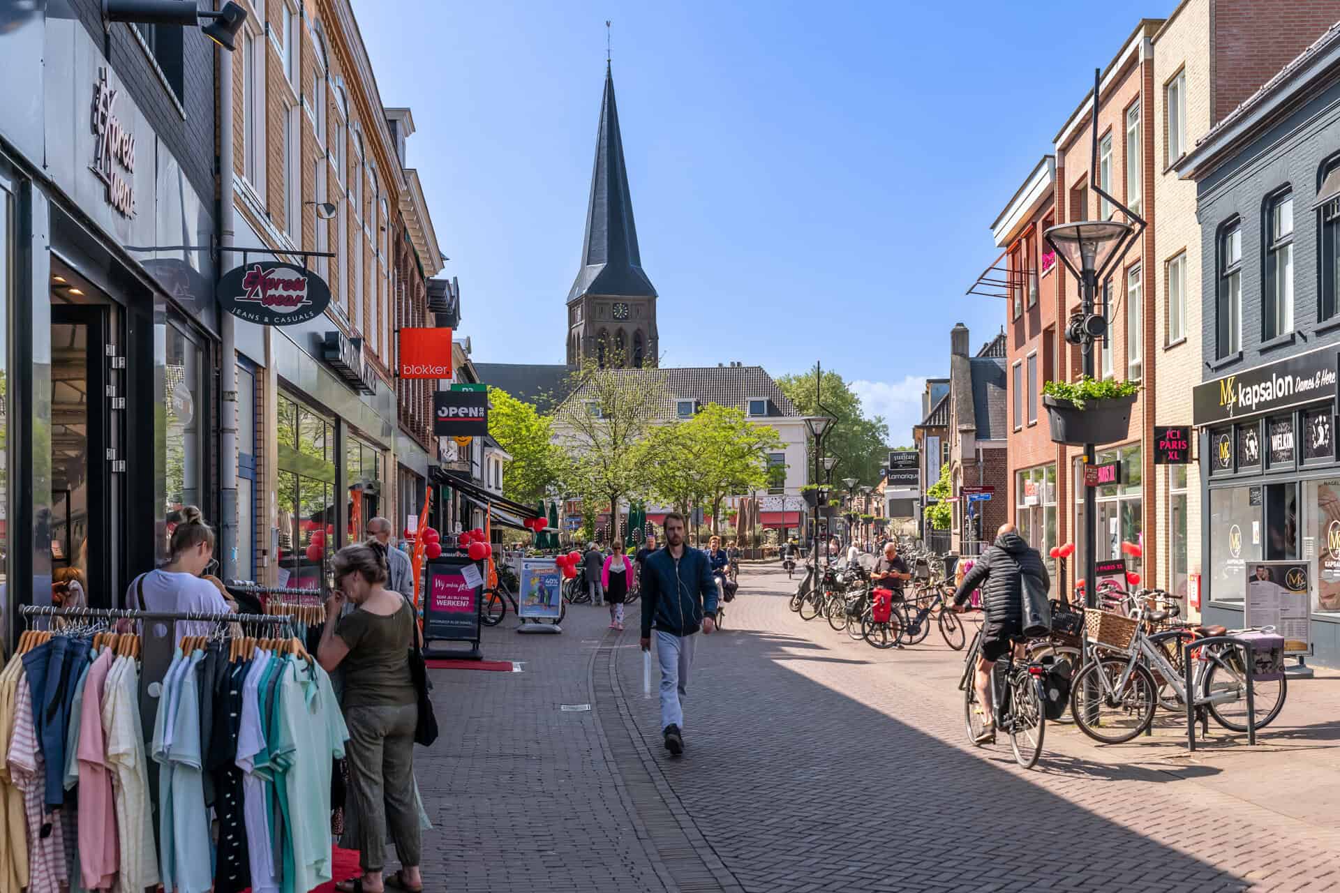Gezellige straat in 't Gelders Eiland met winkels en kerktoren op de achtergrond.