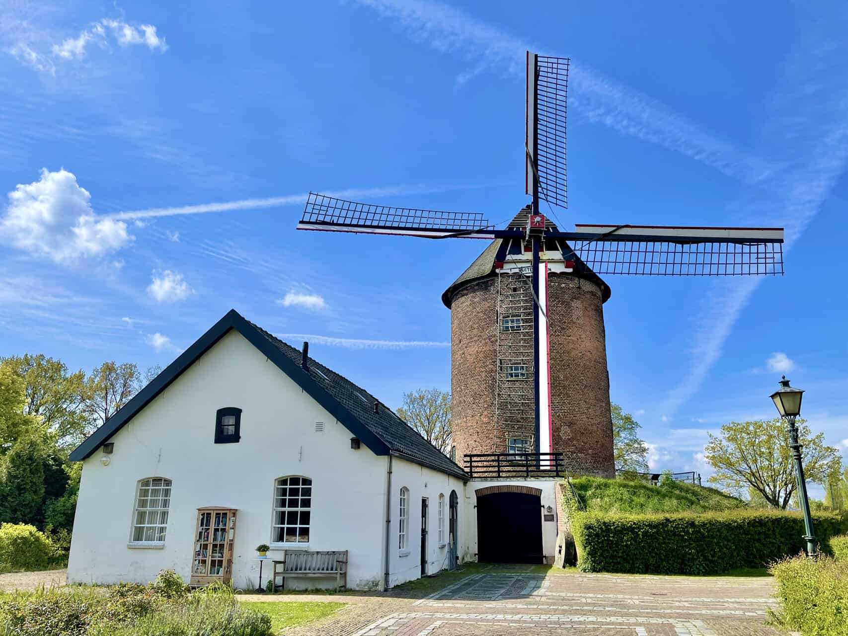 Korenmolen op 't Gelders Eiland onder een heldere blauwe hemel met windrichting en groene omgeving.